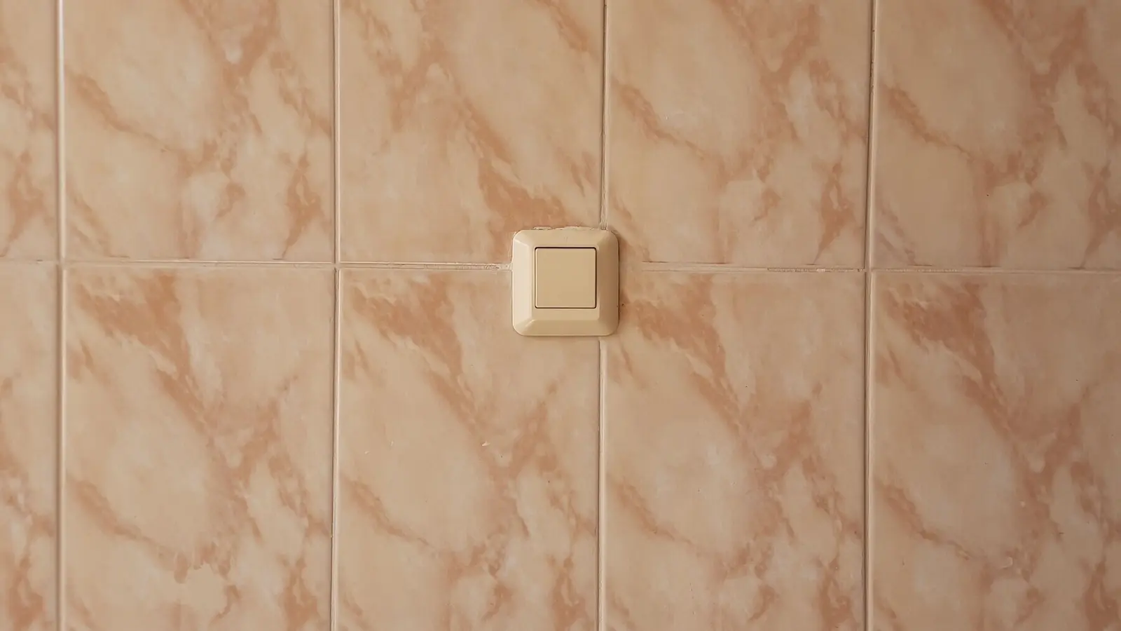 Ściana wyłożona płytkami ceramicznymi z osadzonym w okładzinie włącznikiem światła